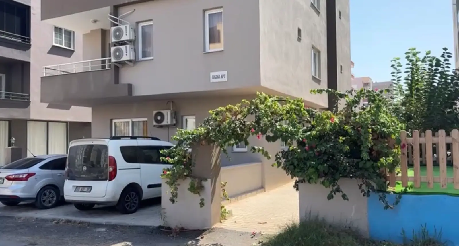 Binanın önündeki parke taşı döşeli otopark, duvarda HazarApt tabelası